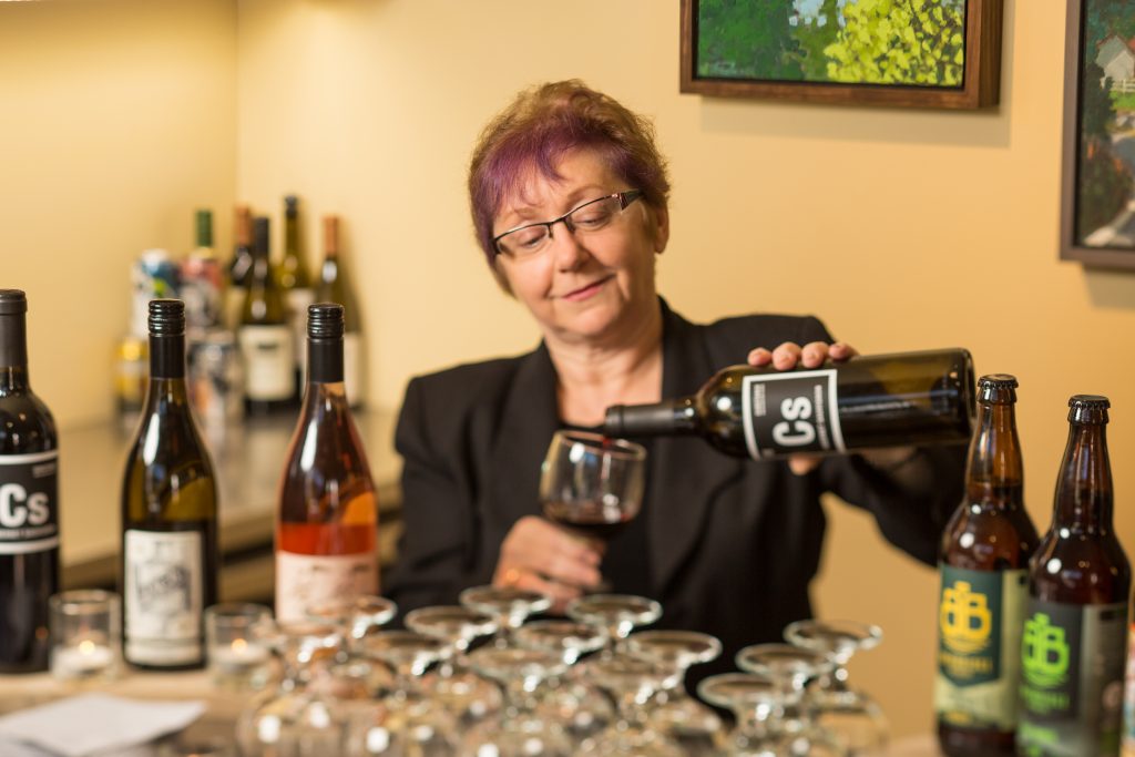 A volunteer pours wine at a BIMA event.