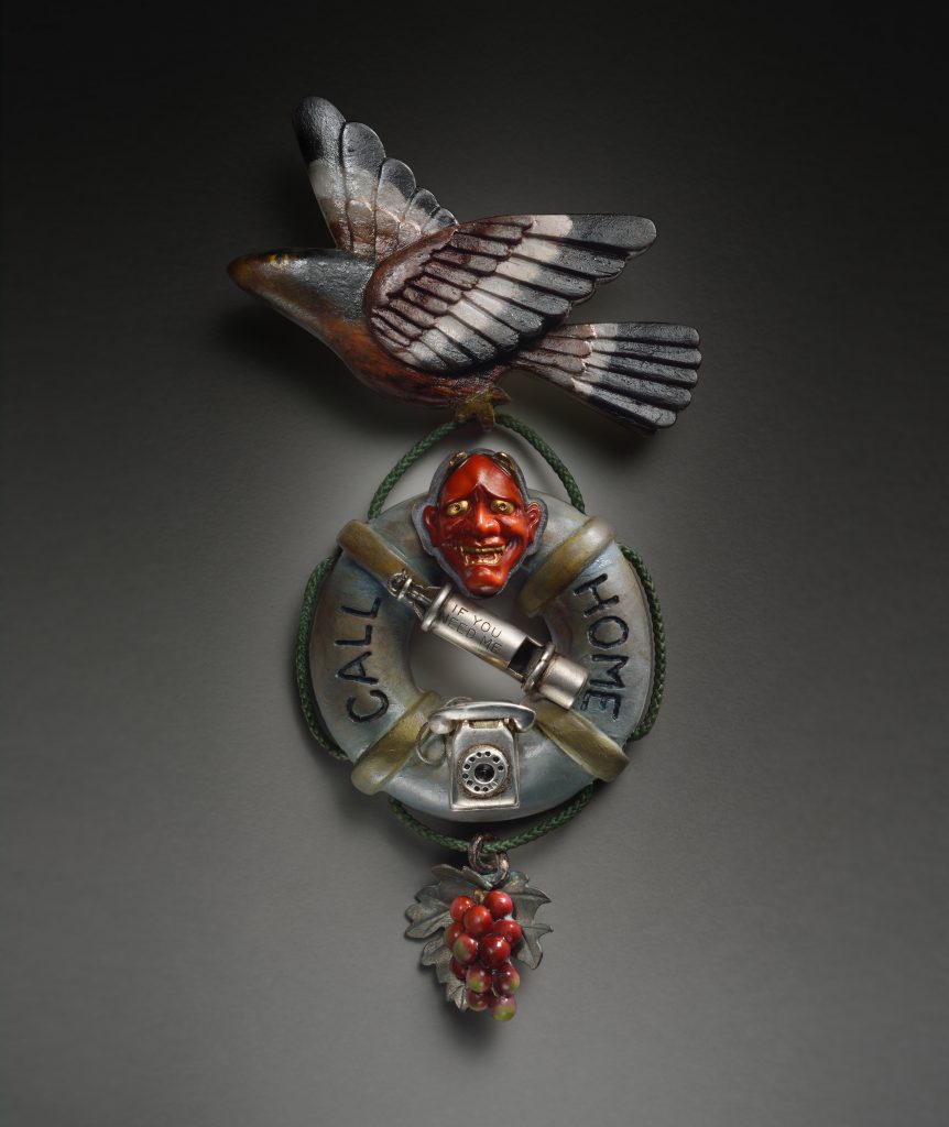 Nadine Kariya, Last Salute to the Camp Bird Generation (Commemorative Medallion), 2015, brooch, carved wood, silver, 18k gold, shibuichi, shakudo, mixed metal, vintage Japanese glass, buttons circa 1940, vintage sterling silver whistle and telephone, steel, nylon and vintage green cord., 6x2.5x.75", Bainbridge Island Museum of Art Permanent Art Collection, Gift of the Artist, Photo Credit: Daniel Fox