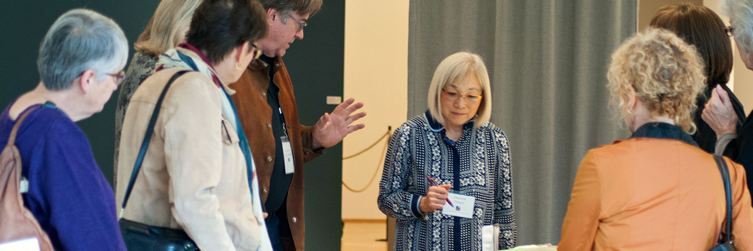 BIMA guests visit with exhibiting artist Steven Maslach as he explains his work.