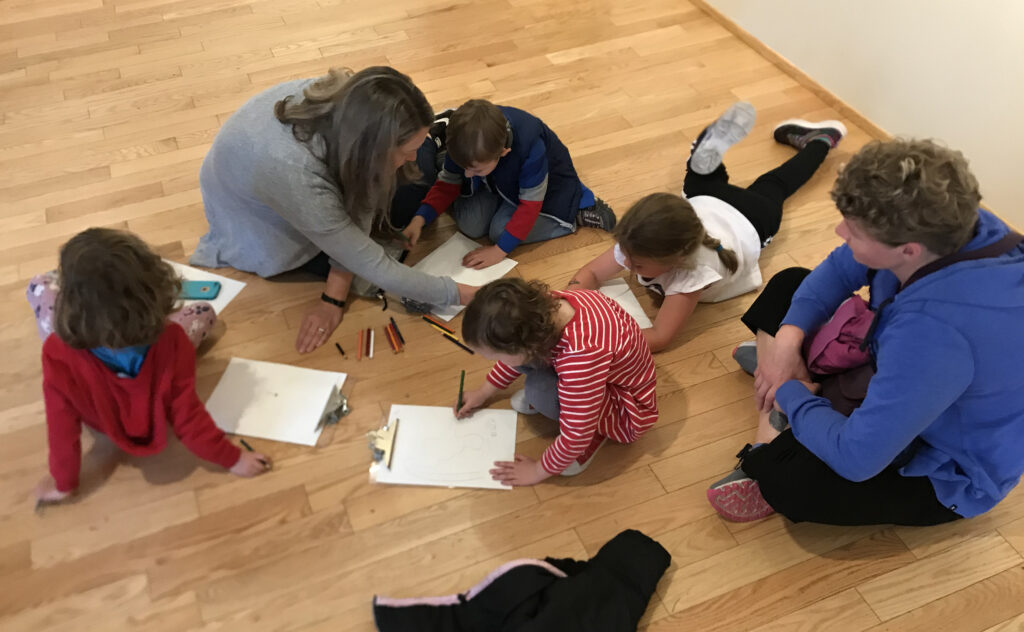 Students sitting on the floor drawing pictures based on their field trip