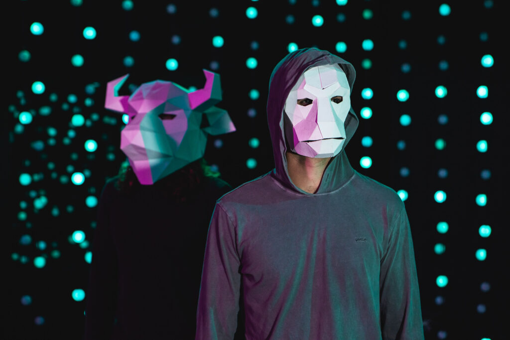 Two members of Terror/Cactus, one wearing a bull mask on the right and one wearing a monkey mask on the left.