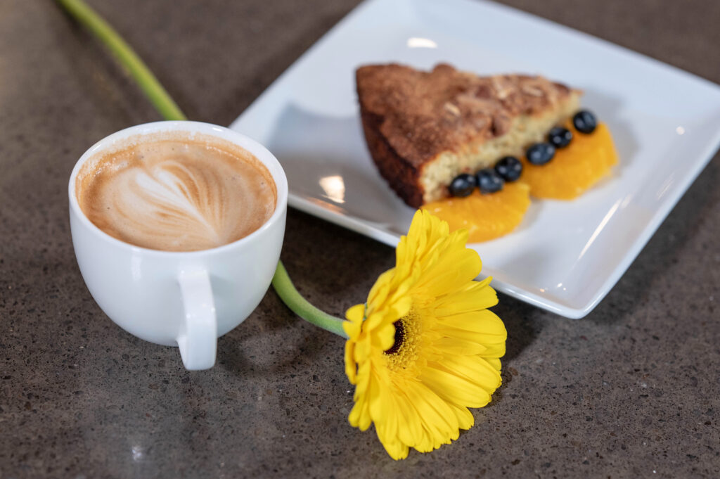 Coffee cake and cup of coffee sit on the counter in the BIMA Bistro