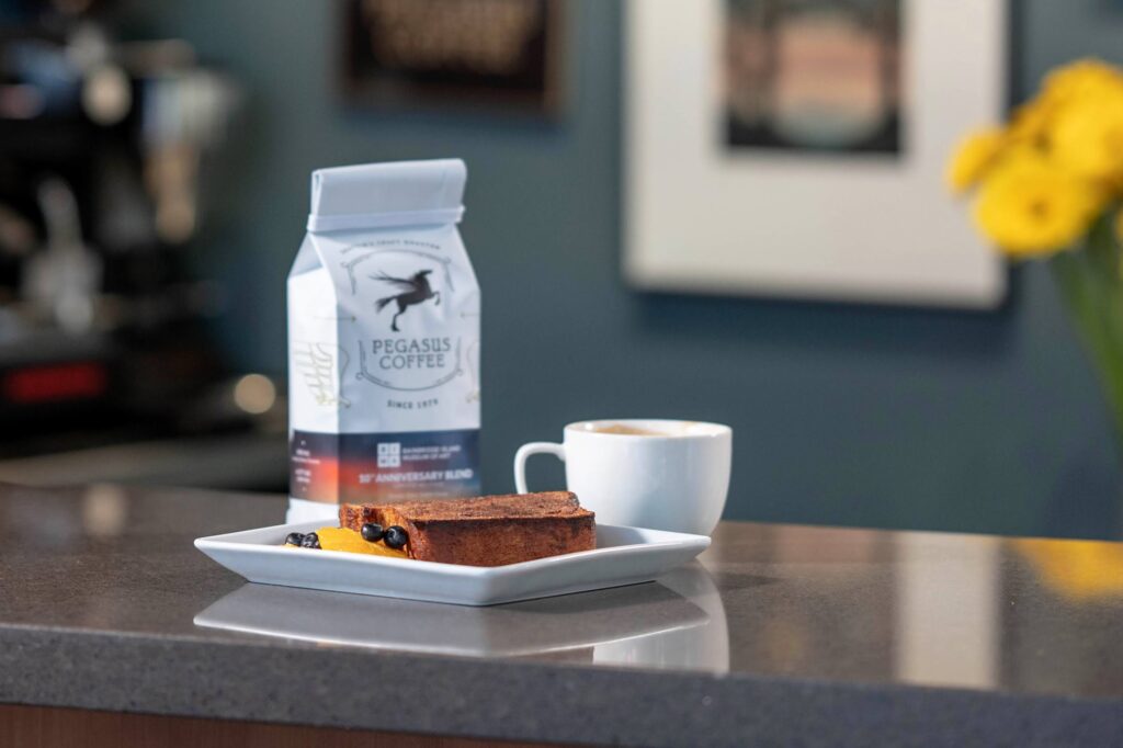 Cinnamon Toast, a pound of Pegasus Coffee, and cup of coffee sit on the counter in the BIMA Bistro