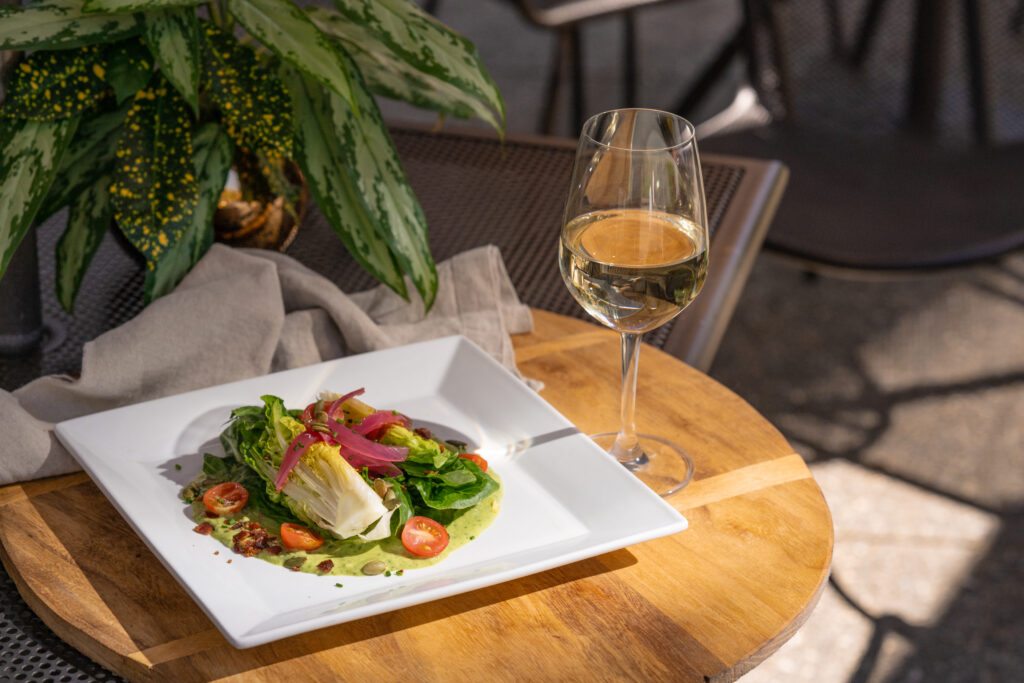 The Green Goddess Wedge Salad served with a glass of wine