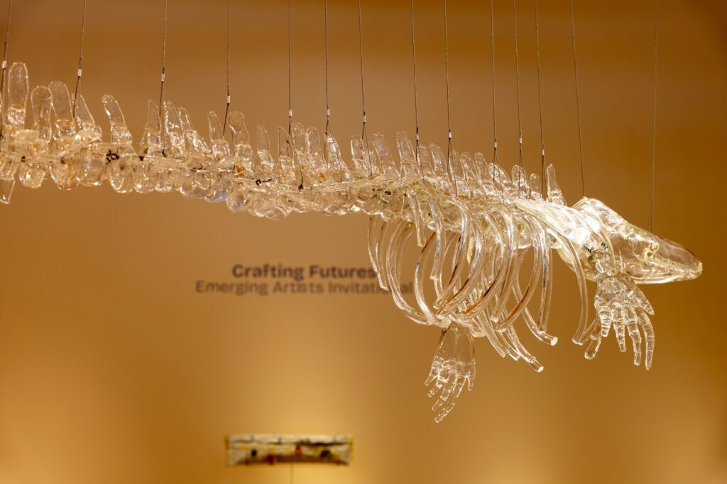 A sculpture of a porpoise skeleton made of glass hangs from the ceiling