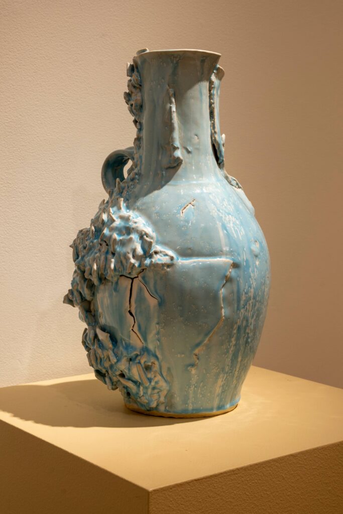 A ceramic vase sits on a tan pedestal