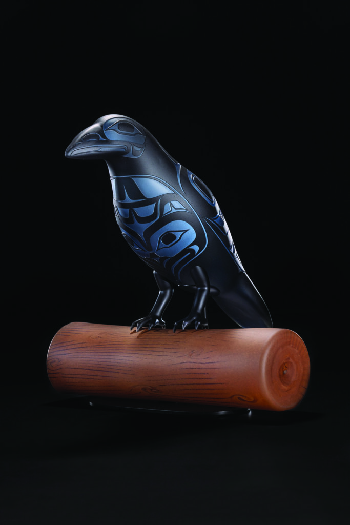 Dark blue carved bird sculpture with tribal patterns perched on a polished wooden log against a black background