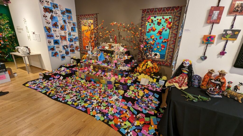 An ofrenda (altar) in the museum is covered in colorful, bright notes, candles, and skulls.