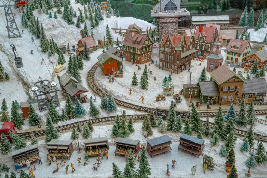 A snowy landscape with red buildings and a train set, all made of miniatures