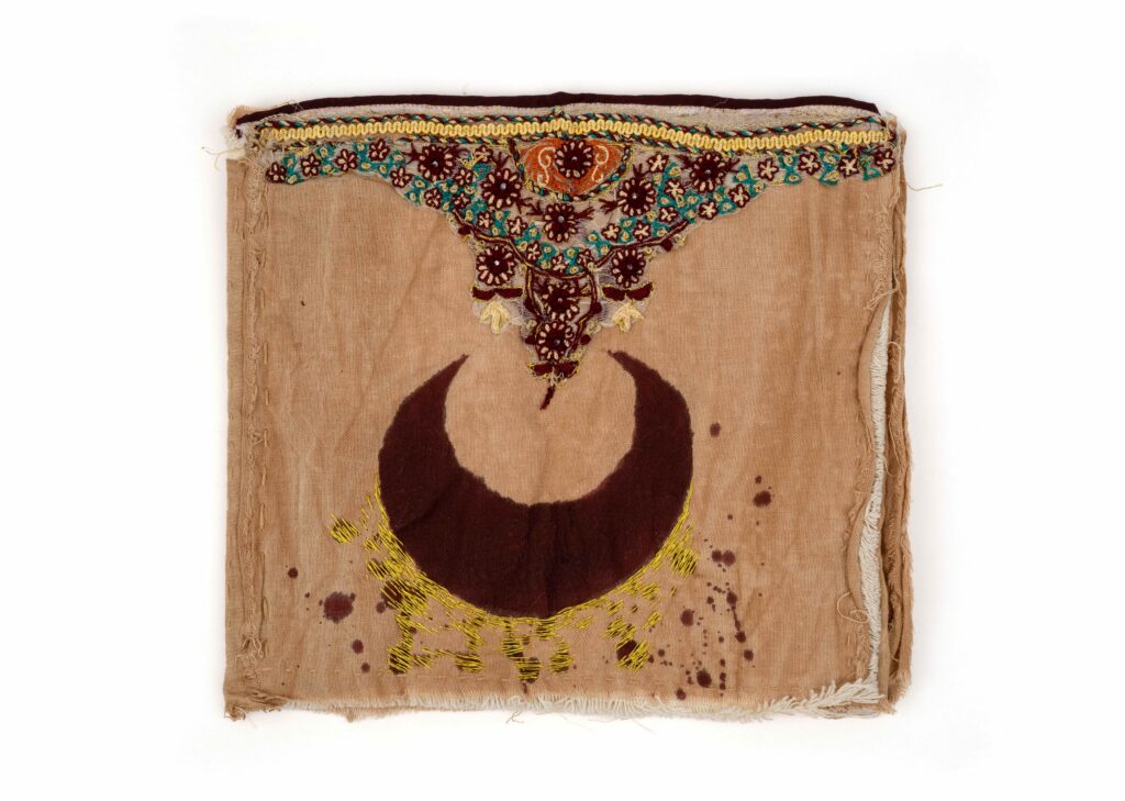 A tan book cover made of thread embroidered on the cover with a moon and florals
