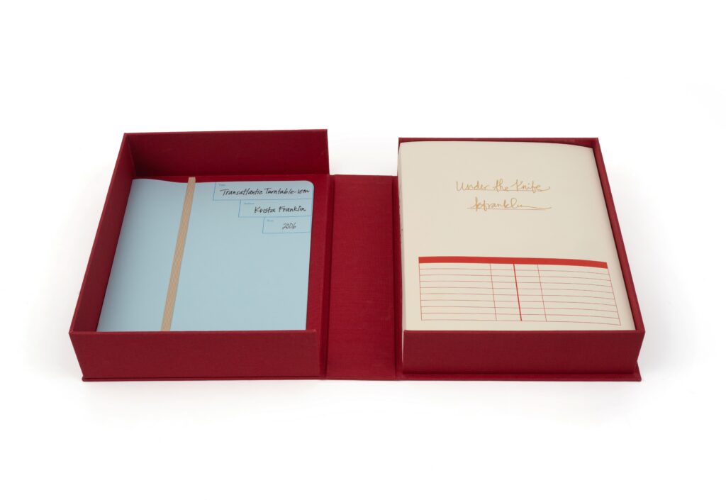 A red box is open with blue papers on the left and a stack of white papers on the right with cursive text