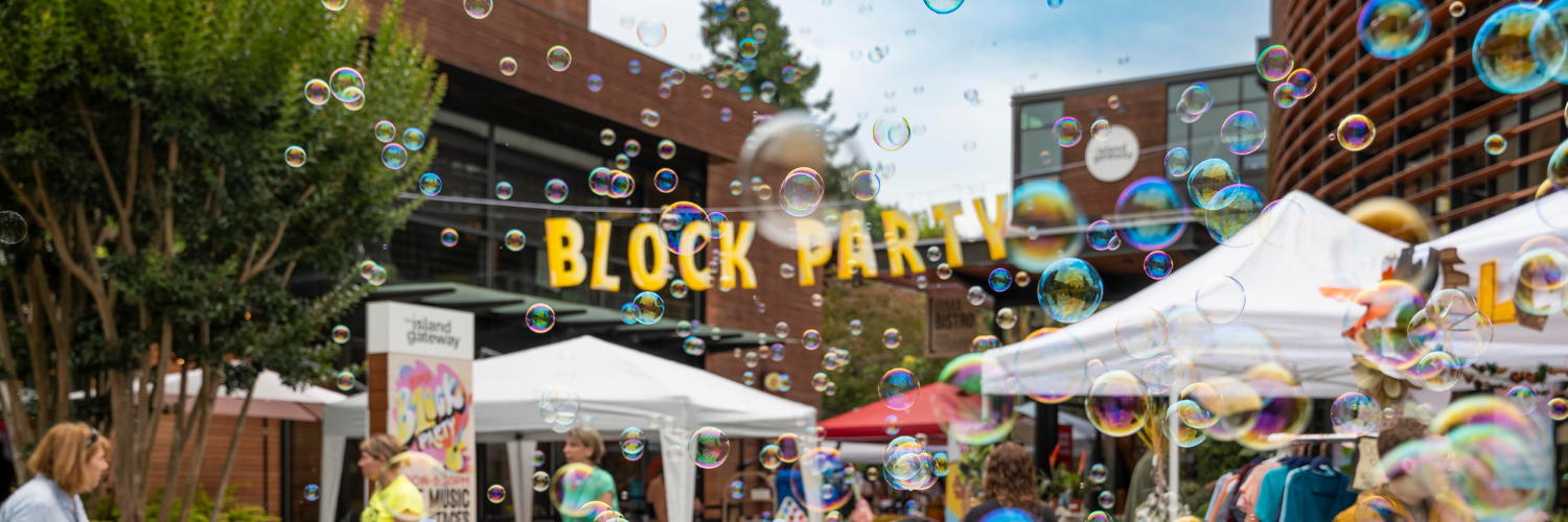Block party street scene with bubbles floating above tents and people wandering between vendor stalls